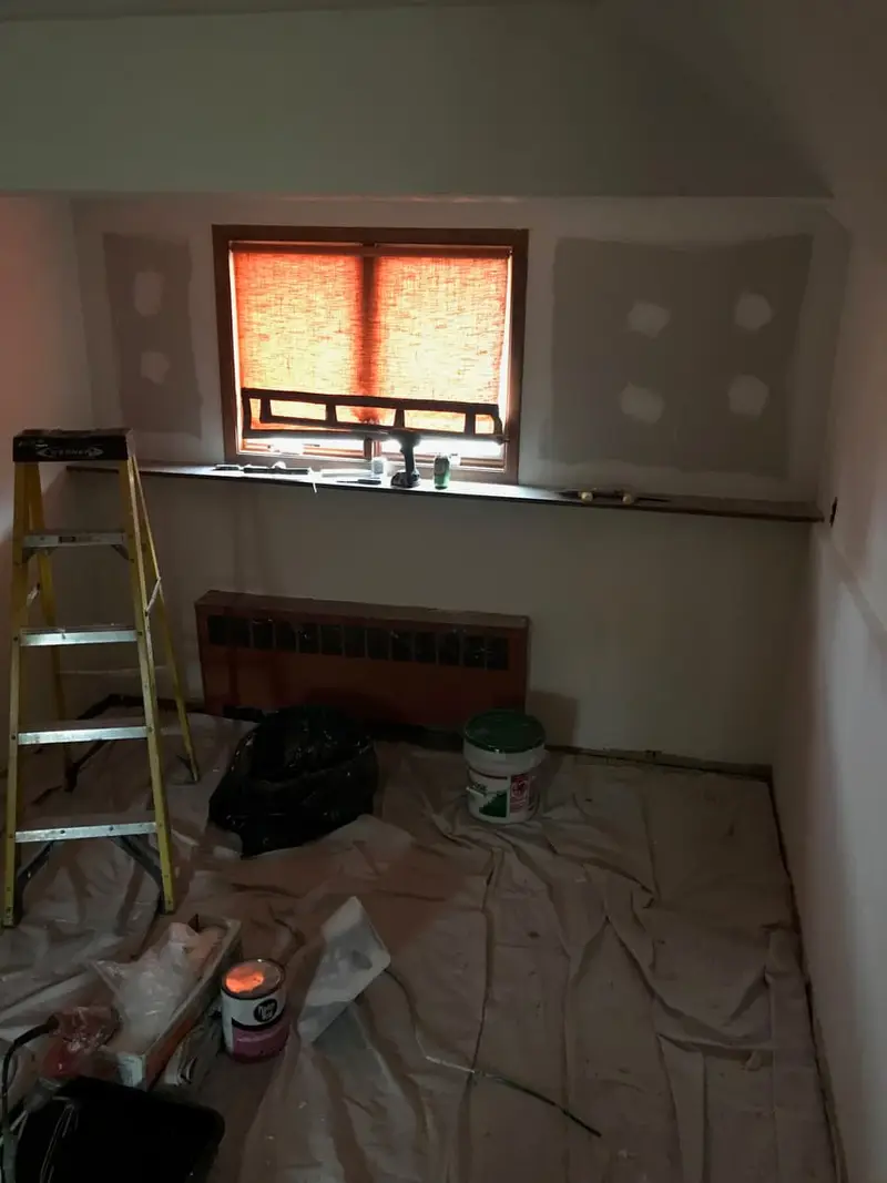 Bedroom mid-renovation with patched walls and drop cloths, Plainview, NY