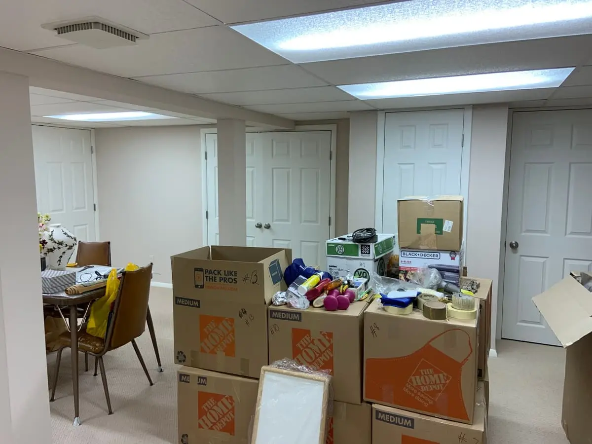 Selling with a non-paying tenant in Plainview: finished basement stacked with moving boxes