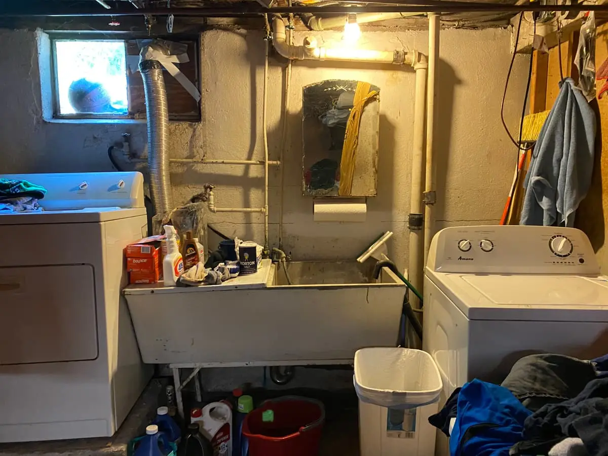 Selling a rental property in Plainview: unfinished laundry area with a utility sink and old washer