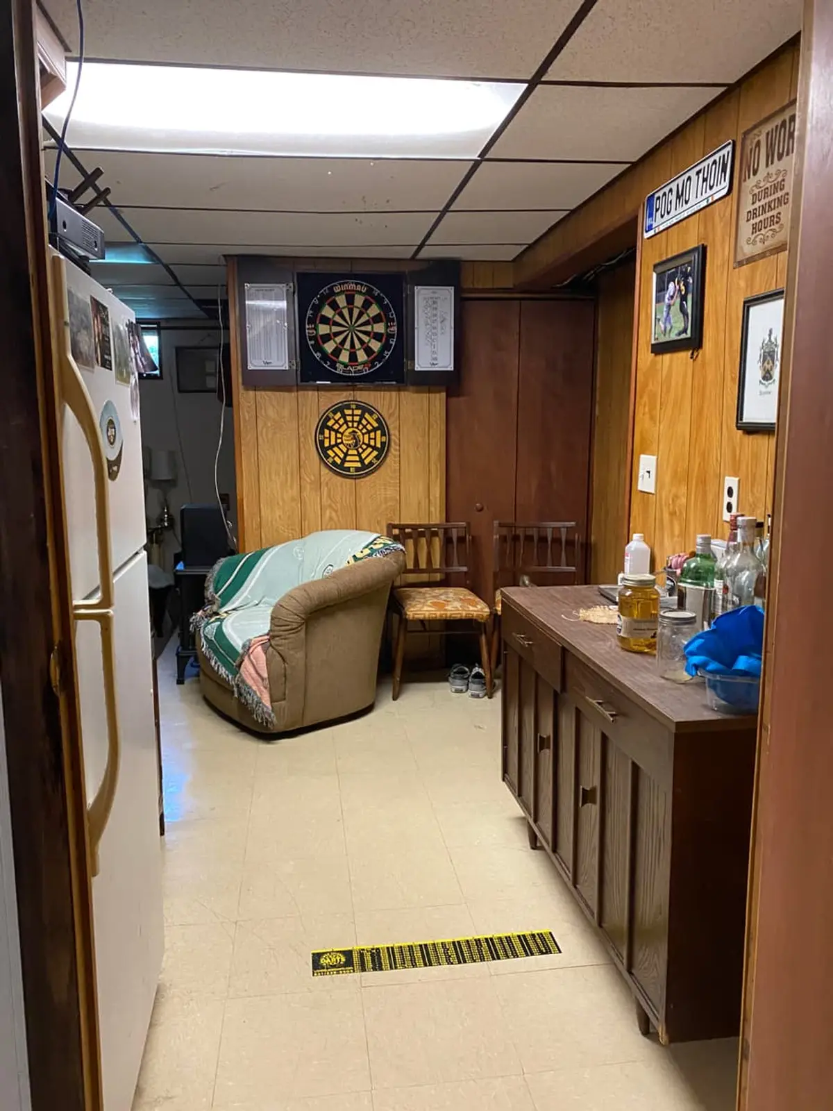 Behind on mortgage payments in Plainview: wood-paneled finished basement with a drop ceiling